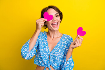 Photo of funky cheerful lady dressed flower print top holding pink heart cover eye isolated yellow color background