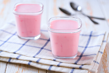 homemade fruit pink yogurt in a glass jars on a white table, selective focus.