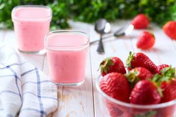 homemade strawberry smoothie in a glass jars with fresh strawberry on a white table, selective focus.