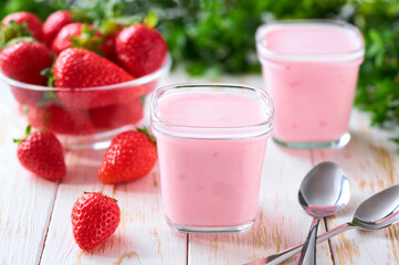 fresh natural homemade strawberry yogurt in a glass jars with fresh strawberry on a light background, selective focus.