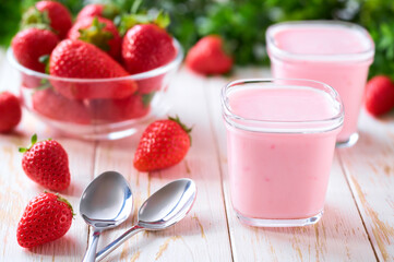 homemade strawberry smoothie in a glass jars with fresh strawberry on a white table, selective focus.