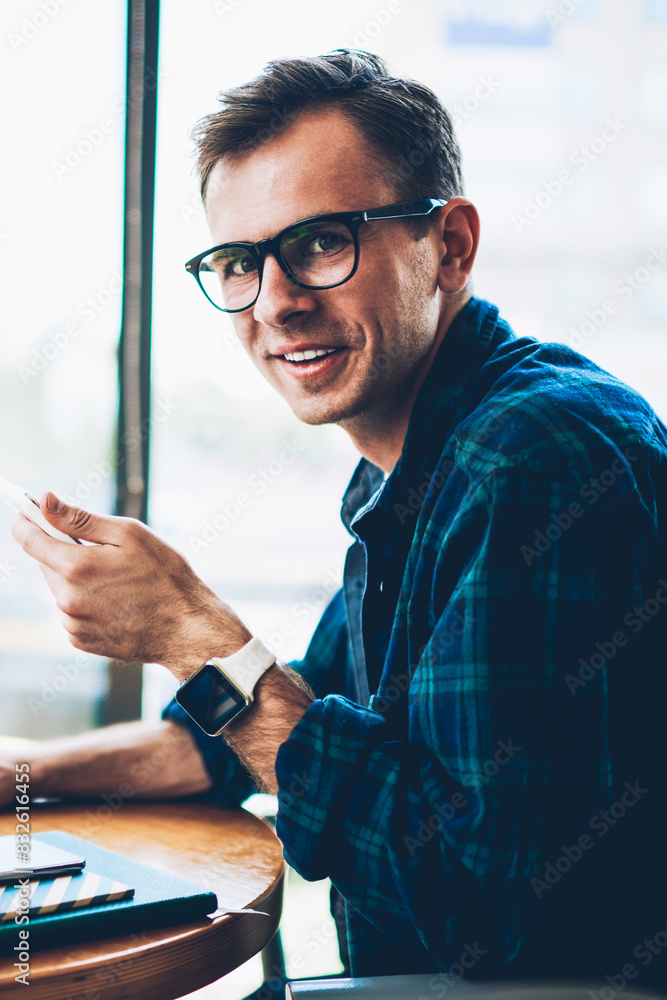 Poster half length portrait of handsome cheerful male developer in cool spectacles using modern technology 