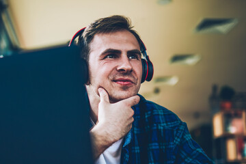 Young good looking positive male person enjoying recreation with big modern headphones and modern...
