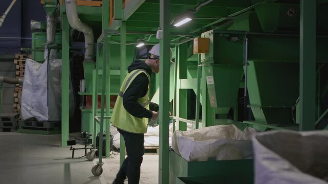Waste management sorting facility caucasian worker conducts an inspection and checks the quality of recyclable plastic. Recycling of garbage. Wearing a hard hat