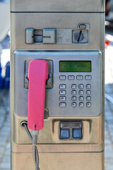 Telefonzelle, alte rote Telefonzelle, altes Münztelefon auf einer Edelstahlsäule, mit rosa Telefonhörer, Tastatur und Münzeinwurf, Deutschland