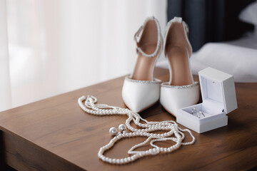 Closeup Bridal accessories with wedding rings. Elegant shoes, perfume, pearl macro photo