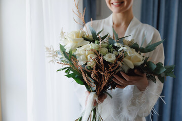 Bride young woman with Radiant Smile Holding modern Wedding Bouquet of White Roses with eucalyptus