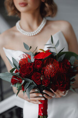 Closeup Modern wedding flowers, bridal bouquet. Decoration made of red roses and decorative plants in hands of bride