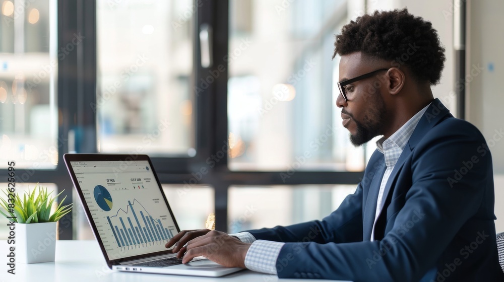 Poster a businessman reviewing stock market data on a laptop screen while working in a modern office enviro