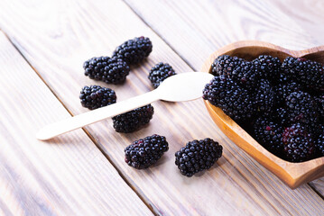 Wooden plate with fresh blackberries on wooden background