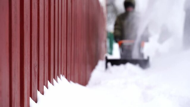 A man removes snow with a snow blower in the yard
