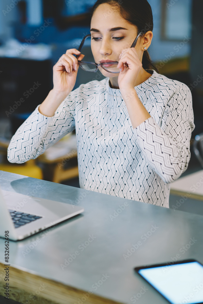 Aufkleber professional female employee putting on spectacles reading financial news from laptop computer in of