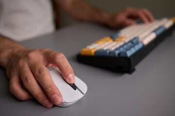 Person typing on keyboard and using a mouse at desk, focused on work technology