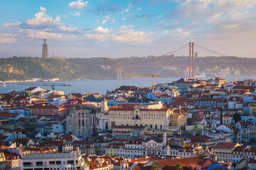 View of Lisbon famous view from Miradouro da Senhora do Monte tourist viewpoint of Carmo Convent Ruins and 25th of April Bridge on sunset. Lisbon, Portugal