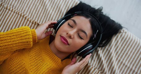 Top view, music and girl in bed for relaxing, resting and comfortable while sleeping in home. Face, radio and podcast with headphones by person in bedroom, daydreaming and chilling with playlist