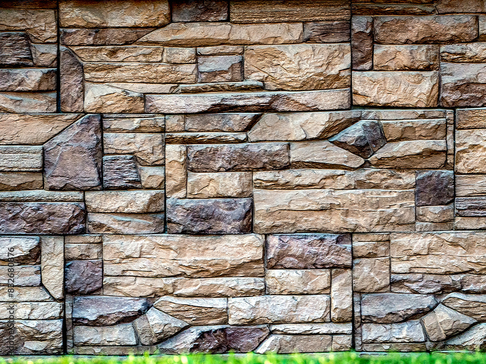 Poster a stone wall of geometric blocks of varying sizes and shapes rises above a narrow strip of grass. st