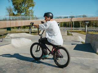 Young BMX bicycle rider smiling, posing in skatepark