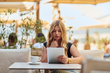 Elegant Businesswoman Enjoying a Productive Break at a Cafe with Her Tablet.