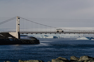 White SUV crossing a remote bridge over icy waters in the Arctic