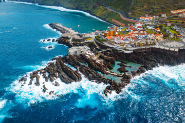 Madeira natural lava swimming pools at Porto Moniz with stormy waves Atlantic ocean, Aerial view