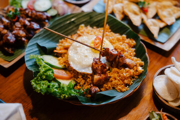 Nasi goreng with fried egg and skewers served on a banana leaf