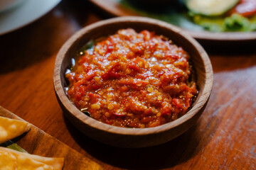 Spicy chili paste in wooden bowl on wooden table
