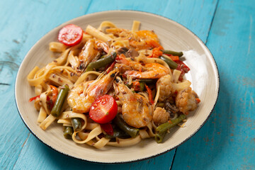 shrimp and udon vegetables pad thai sauce on a blue table. copy space