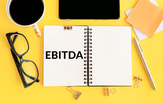 EBITDA Concept Highlighted on an Open Notebook Against a Yellow Background
