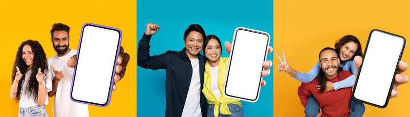 Multiethnic couple lovers showing smartphones with white blank screens, posing on colorful...