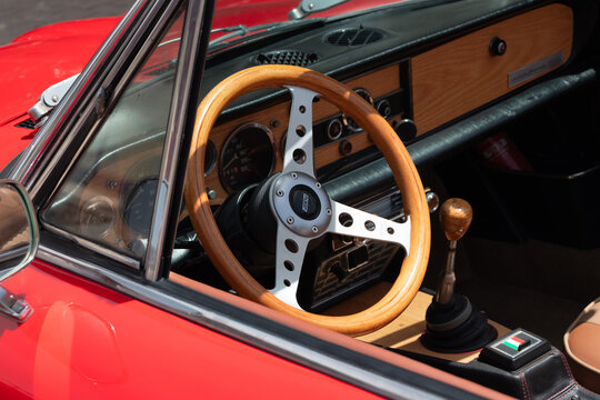 Mitzpe Ramon, Israel- May 10,2024: Fiat 124 Sport Spider wooden steering wheel and dashboard closeup on red antique collector convertible car 