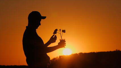 The silhouette of an agronomist holding a pot with a plant ready for planting is visible.