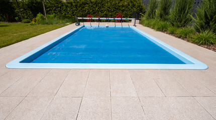 Home outdoor pool covered with film to save chemicals, water and heat preservation