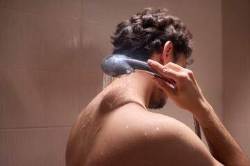 Naklejka premium A man is taking a shower, enjoying the clean water to ensure good hygiene and relaxation