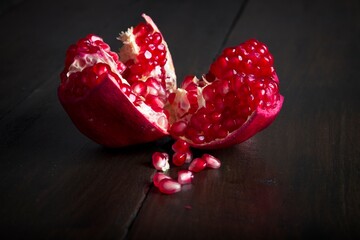 Close-up of ripe, fresh pomegranate cut open with view of seeds on a wooden table
