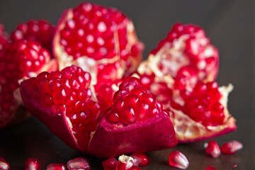 Close-up of ripe, fresh pomegranate cut open with view of seeds on a wooden table