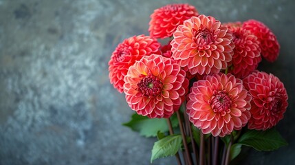   A red bouquet sits on a gray table, near a green plant and gray wall