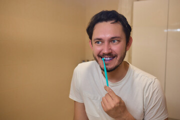 A man with blue teeth looks amused in a closeup shot, with a spontaneous and vibrant expression...