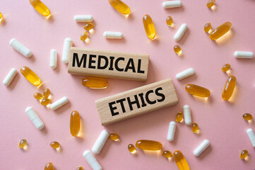 Medical Ethics symbol. Concept word Medical Ethics on wooden blocks. Beautiful pink background with...