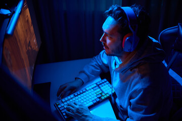 A coder is working late at night on a computer screen, coding and using a smartphone app