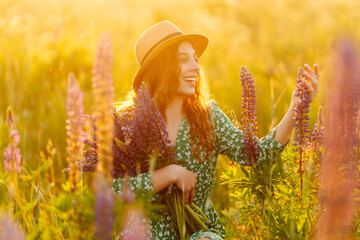 Beautiful woman holding bouquet of lavender flowers walking in summer meadow. Collection of medicinal herbs