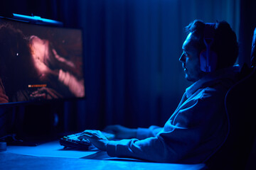 A coder is working late at night on a computer screen, coding and using a smartphone app