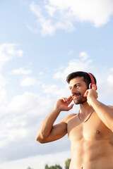 Athlete man listening to music with headphones. man doing sports outside listening to music
