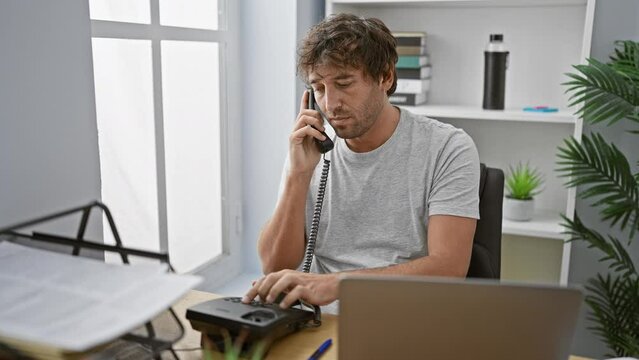 Handsome businessman with beard talking on phone in modern office, displaying concentration and workplace routine.