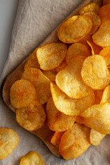 Cheese Potato Chips on a Wooden Board, top view. Flat lay, overhead, from above. Close-up.