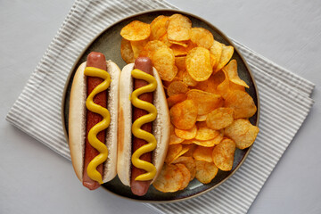 Homemade Hot Dog with Mustard and Potato Chips on a Plate, top view.