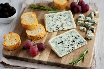 Organic Blue Cheese with Grapes and Olives on a Wooden Board, side view.