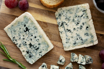 Organic Blue Cheese with Grapes and Olives on a Wooden Board, top view.