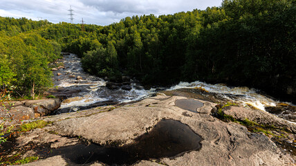 A river flows through a lush green forest with surrounding natural landscape