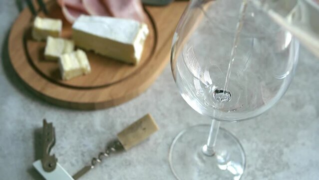 Close-up of pouring Spanish white wine Albari&ntilde;o into a wine glass on a marble table
