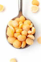 Dry, yellow peas in iron spoon on white background. Close-up